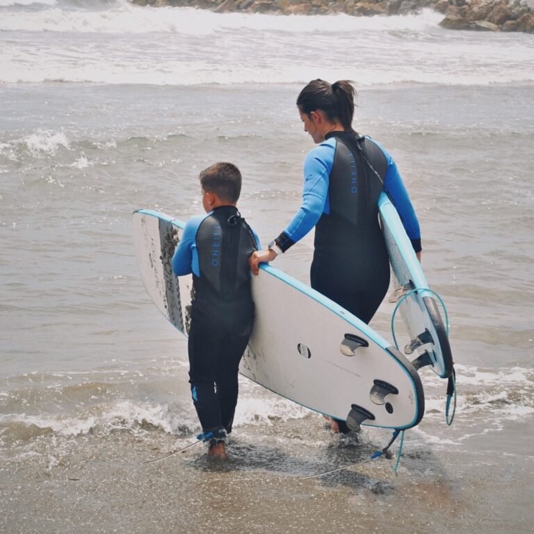 Madre e hijo entrando al mar con tablas de surf