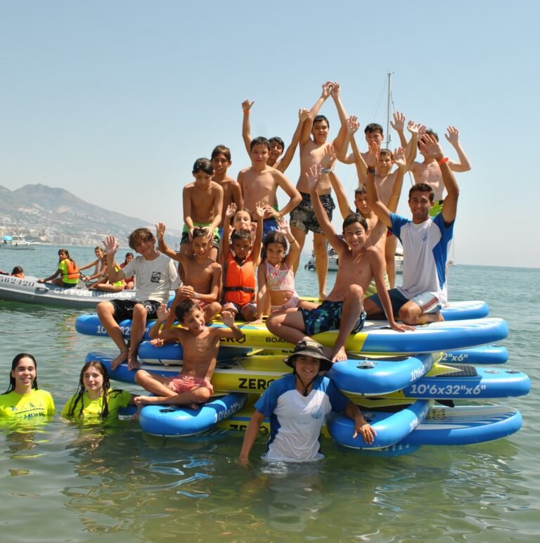 Grupo de niños celebrando un cumpleaños sobre tablas de paddle surf en el mar